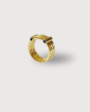 Gold 3 Band ring with small black stones on a light gray background