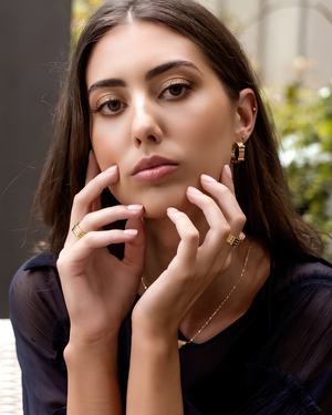 Model wearing CVLCHA ADIRA gold rings, with a outdoor background
