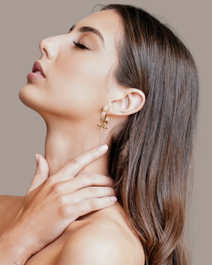 Model wearing CVLCHA ADIRA Rod Hoop Earrings featuring a sculptural hoop design with polished rod detail and signature chain drop.