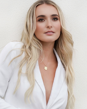 Female wearing CVLCHA Capricorn Zodiac Gold Necklace with white blazer
