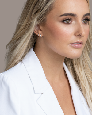 A close up of a blonde women wearing the CVLCHA Double Hoop Huggie Earrings styled for an effortless layered ear look with a single piercing.