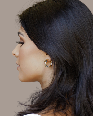 Side profile of model wearing CVLCHA EDGE Sapphire Blue Hoop Earrings featuring premium 5A sapphire blue cubic zirconia in a contemporary gold hoop design.