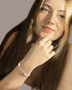 A close-up lifestyle shot of a woman wearing the Emily freshwater pearl bracelet styled with modern layered jewellery by CVLCHA.
