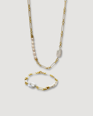 A gold-toned jewelry set featuring a long chain necklace and a matching bracelet, both decorated with small white pearls and a larger white baroque shell on a light gray background.