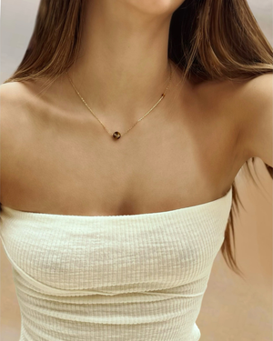 Up close photo of a Female wearing the Cvlcha Iris Tiger Eye gemstone Pendant Gold Necklace in an outdoor setting
