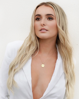 Woman wearing a CVLCHA Leo Gold Necklace with a white top on a plain background