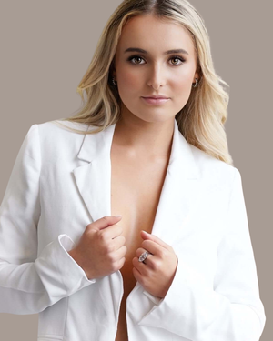 Woman wearing a white blazer with a beige background wearing the Cvlcha Lumina Silver ring with a striking marquise cut 5A clear colour zirconia