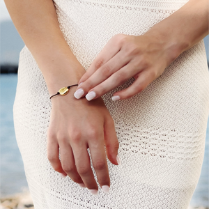 Close-up of a person wearing the Mila Gold Bead Leather Bracelet by CVLCHA styled with layered gold jewellery and modern neutral fashion.